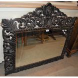 A STAINED OAK BEVELLED GLASS WALL MIRROR WITH STYLISED FLORAL MOTIFS AND LION HEAD SURMOUNT, APPROX.