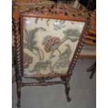 A VICTORIAN WALNUT FIRE SCREEN WITH SPIRAL CARVED UPRIGHTS ENCLOSING PRINTED FLORAL PANEL
