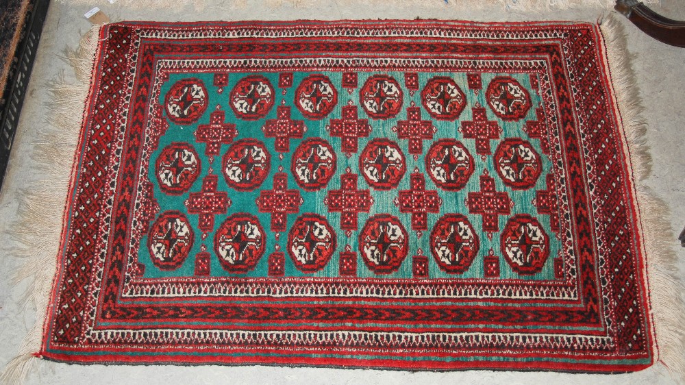 A SMALL PERSIAN RUG, THE RECTANGULAR GREEN GROUND DECORATED WITH THREE ROWS OF SIX OCTAGONAL