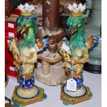 A PAIR OF CANTAGALLI STYLE POTTERY CANDLESTICKS IN THE FORM OF WINGED MYTHICAL BEASTS HOLDING