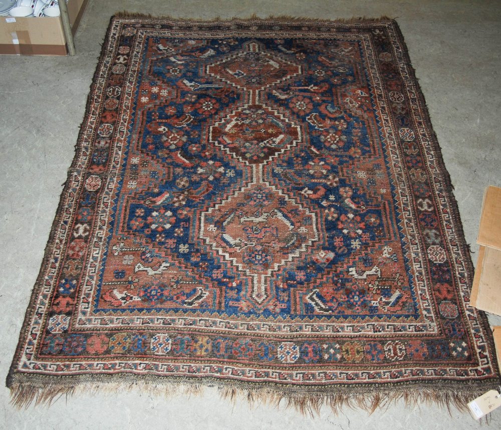 A PERSIAN RUG, THE BLUE RECTANGULAR GROUND CENTRED WITH THREE LOZENGE SHAPED MEDALLIONS WITHIN A