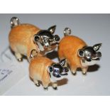 A SET OF THREE SILVER AND ENAMEL GRADUATED PIGS