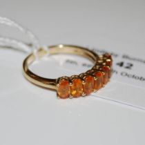 A 9CT GOLD AND ORANGE SAPPHIRE RING, SET WITH SEVEN OVAL CUT ORANGE SAPPHIRES, ESTIMATED TO WEIGH