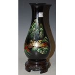 A BLACK GROUND LACQUERED VASE ON INTEGRAL STAND