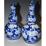 A PAIR OF CHINESE PORCELAIN BLUE AND WHITE DOUBLE-GOURD VASES AND COVERS, DECORATED WITH PRUNUS