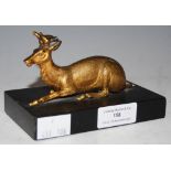 A GILT METAL FIGURES OF A RECUMBENT STAG ON A RECTANGULAR POLISHED SLATE PLINTH