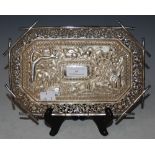 AN INDIAN WHITE METAL OCTAGONAL-SHAPED TRAY WITH EMBOSSED DECORATION OF ANIMALS WITHIN PIERCED