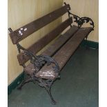 A GARDEN BENCH WITH BLACK PAINTED CAST METAL BRANCH-FORM ENDS DECORATED WITH LEAVES AND BERRIES