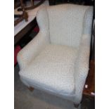 A WING-BACK ARMCHAIR WITH CREAM UPHOLSTERY AND BLUE FLORAL DETAILS