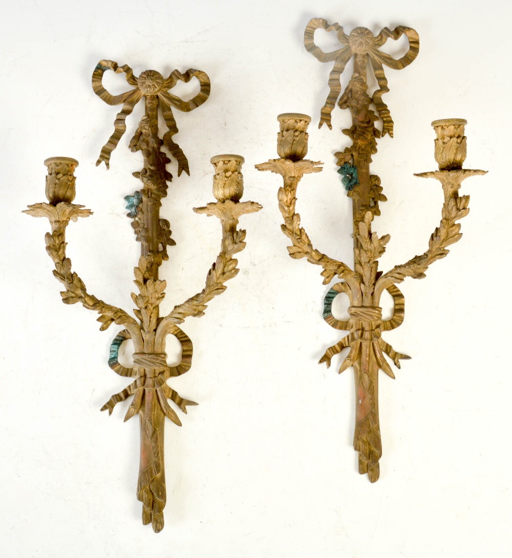 A pair of late 19th century gilt metal two light wall sconces, with ribbon tied and foliate cast