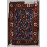 A Persian rug, 20th century, the blue rectangular field decorated with rows of stylised flowers