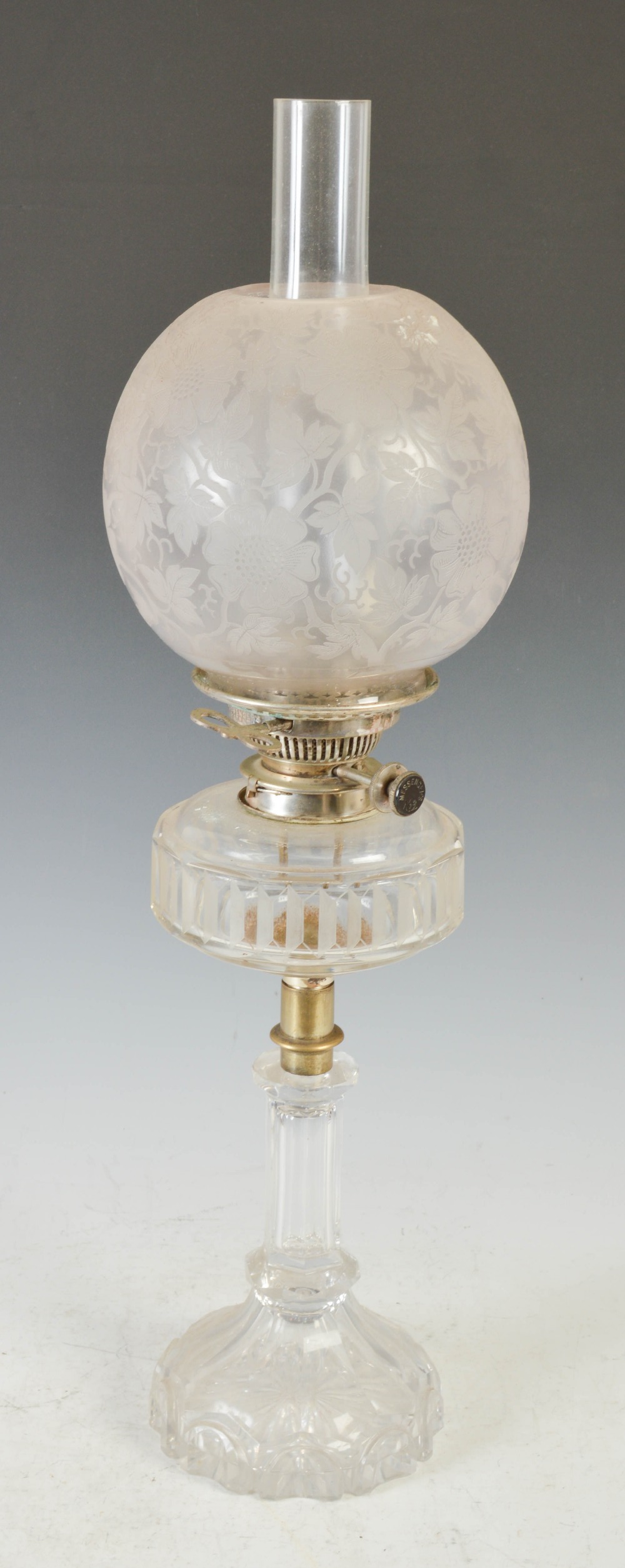 A late 19th/ early 20th century white metal mounted glass oil lamp, with frosted glass shade, the