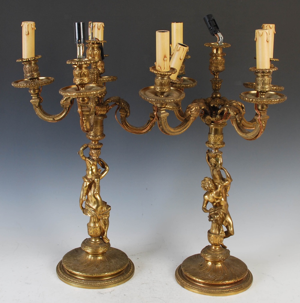 A pair of late 19th/ early 20th century gilt metal five light candelabras, with urn shaped nozzles