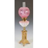 A late 19th/ early 20th century brass oil lamp, with ruby tinted glass shade, the burner section
