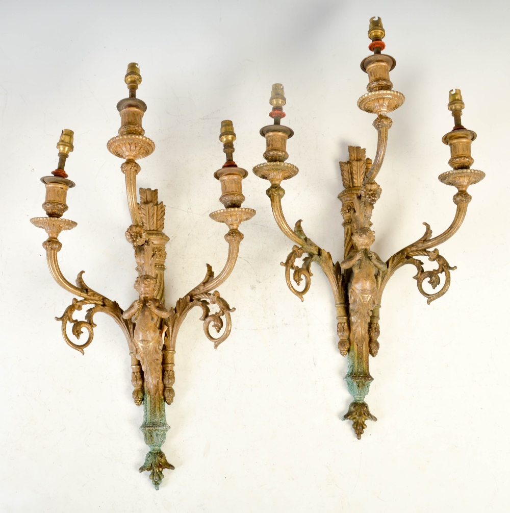 A pair of late 19th century gilt metal three light wall sconces, each cast with a cherub playing