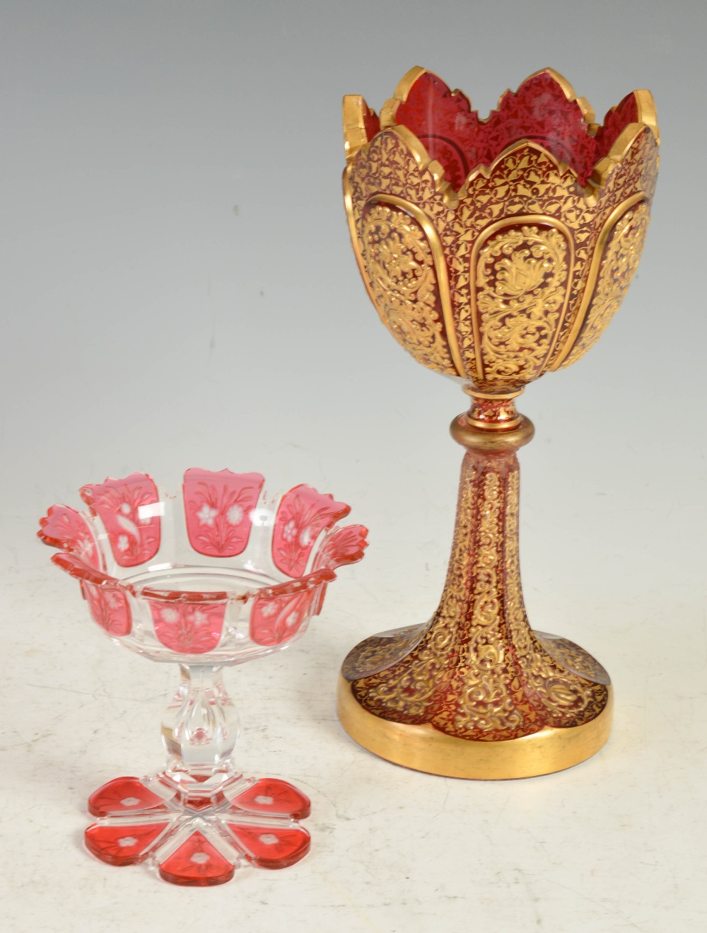 A late 19th century Bohemian ruby glass goblet, decorated in relief with panels of flowers and