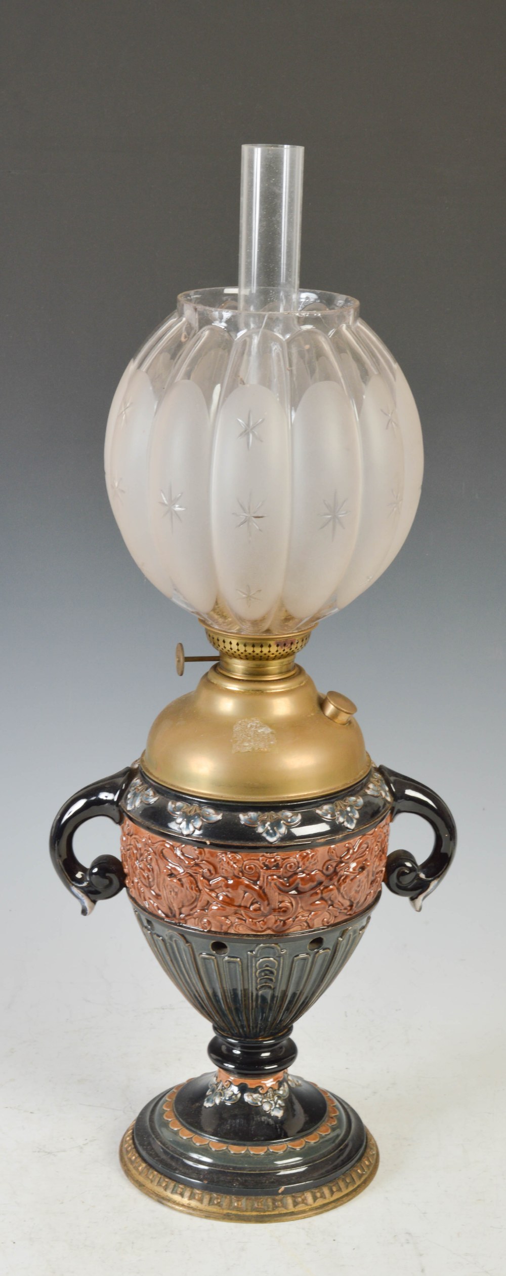 A late 19th/ early 20th century pottery oil lamp, the clear and frosted glass shade of lobbed form