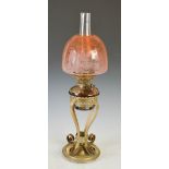 A late 19th/ early 20th century brass oil lamp, with brown glazed ceramic reservoir and peach tinted