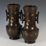 A pair of Japanese bronze twin handled vases, late 19th/ early 20th century, decorated in shallow