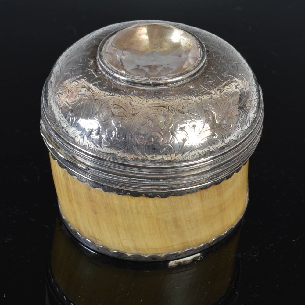 An early 19th century horn circular table snuff box, the domed silver cover profusely engraved