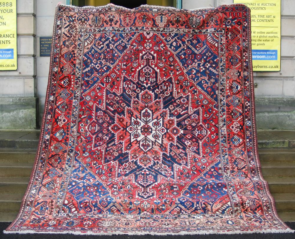A Persian rug, 20th century, the rectangular field centred with a large open stylised flower