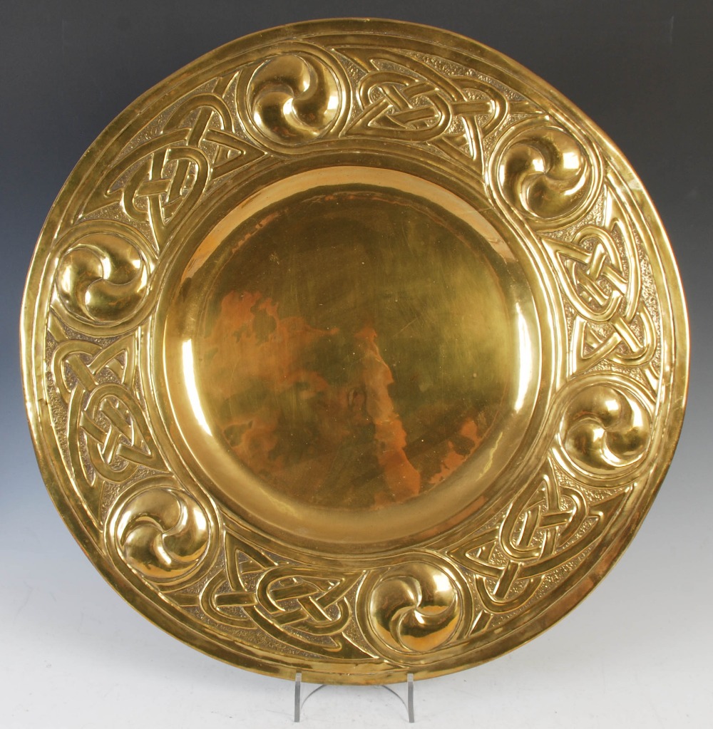 An early 20th century Scottish Arts and Crafts brass charger, with embossed decoration of six