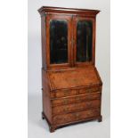 A George III walnut bureau bookcase, the moulded cornice above a pair of mirrored cupboard doors,