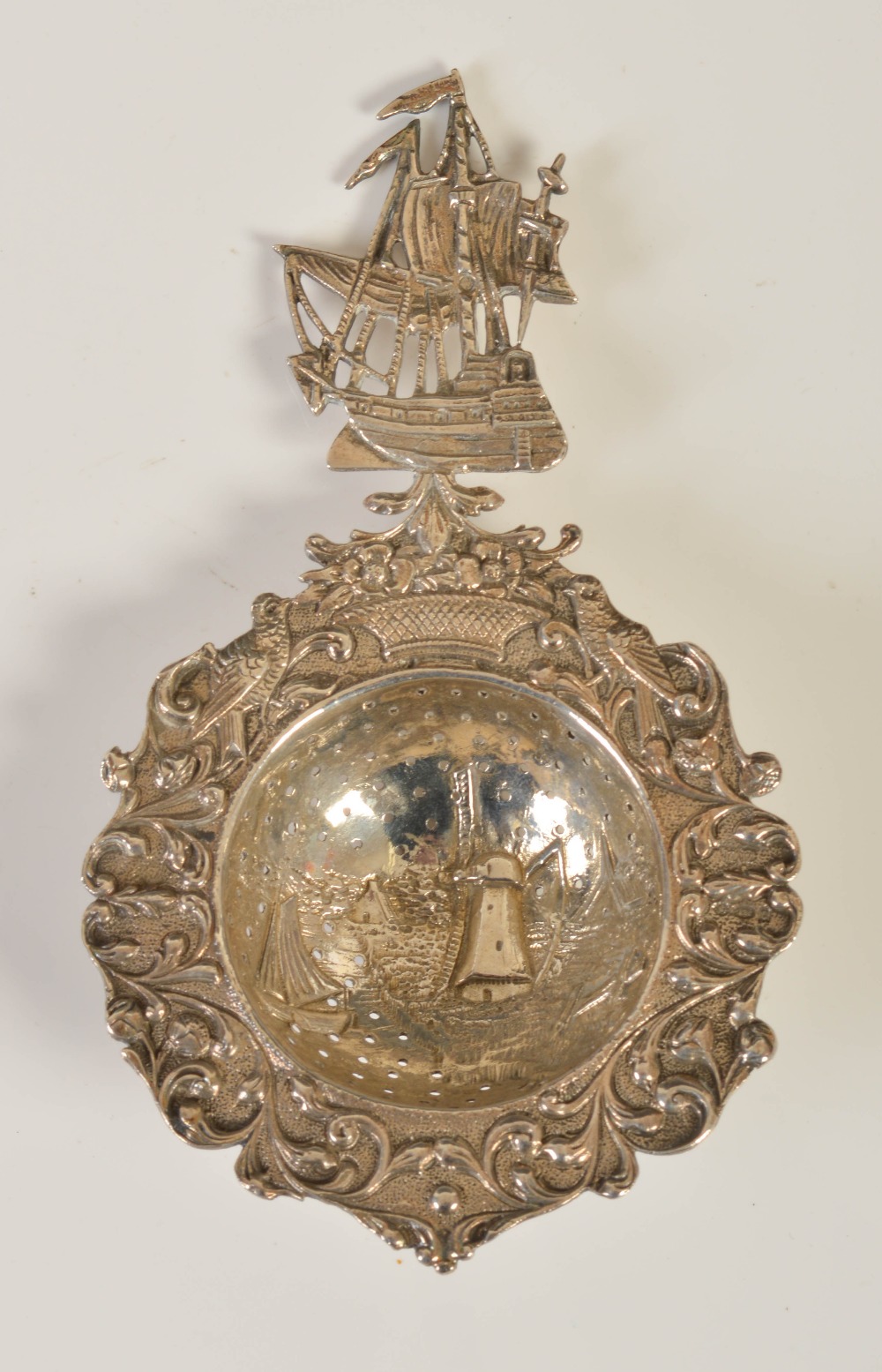 A 19th century Dutch white metal tea strainer, the handle formed as a pieced three masted galleon,