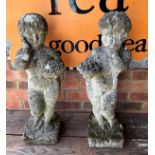 Pair of country house style, well weathered composite stone garden cherubs holding baskets of