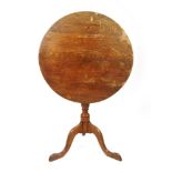 An 18th century oak tilt top tripod table, the circular top on a turned column and three legs, h.