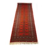 A handwoven Afghan runner, the multi line border surrounding a red ground field,