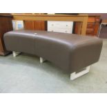 A brown upholstered padded curved bench