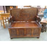 A carved oak monk's bench with shield design to backrest