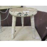 A small three-legged white painted stool