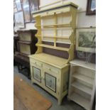 An early 20th century cream painted dresser having a plate rack to top and the base having two