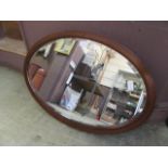 An Edwardian mahogany boxwood strung bevel glass oval mirror