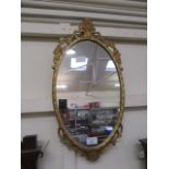 An ornate gilt metal framed oval mirror