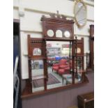 An early 20th century walnut over mantle mirror having bevelled glass and shelves with turned