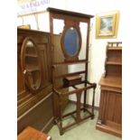 An early 20th century walnut hall stand, oval bevel glass flanked by hooks over stick stand