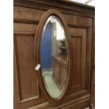 An Edwardian mahogany boxwood strung oval bevel glass mirror