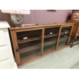 An early 20th century oak wall hanging bookcase with three glazed sliding doors