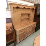 A pine dresser, the plate rack with cupboard doors flanking open shelving and four spice drawers