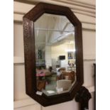 An early 20th century oak framed bevel glass mirror with ivy design