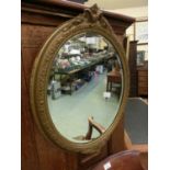 An ornate gilt framed oval bevel glass mirror