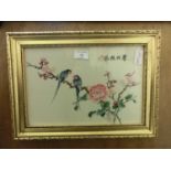 A framed and glazed oriental needlework of parrots on flowering branch