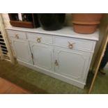 A grey painted dresser base having three drawers above cupboard doors