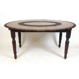 A 19th century Anglo Indian teak dining table, the carved oval top on four carved legs, h. 76 cm, w.