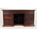 An early 20th century Japanese carved miniature table desk, the top over long drawer above open