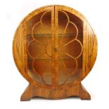 An Art Deco walnut display cabinet, the circular body with two glazed doors on splay base, h. 120