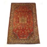 A handwoven Persian rug, the multi line border surrounding a red ground field with arabesque